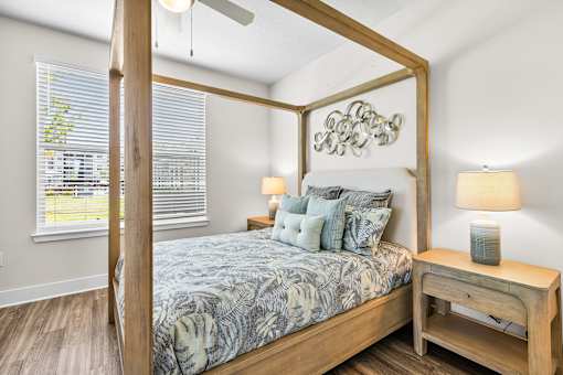 A bedroom with a four poster bed and a wooden nightstand.