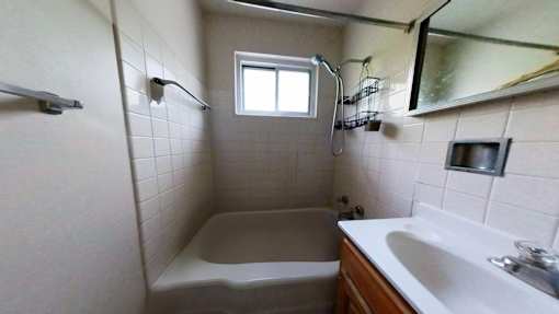 A small bathroom with a tub, sink, and mirror.