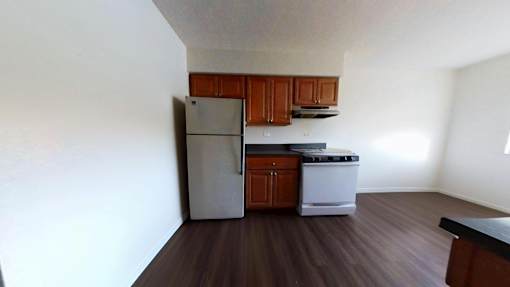 A kitchen with a refrigerator, stove, and cabinets.