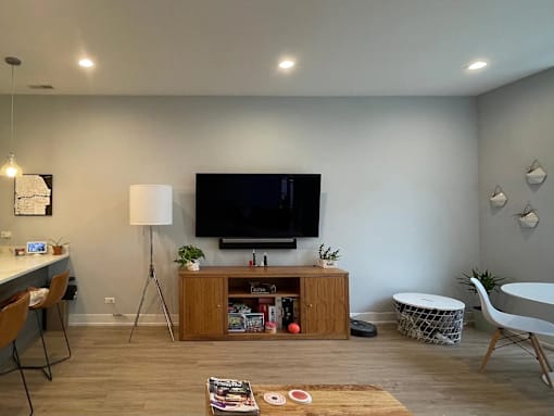 A living room with a television, a table, and a chair.
