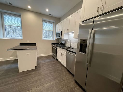 A kitchen with a refrigerator, oven, and microwave.