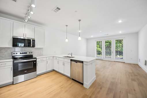 A modern kitchen with wooden floors and white cabinets.