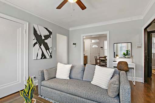 A living room with a grey couch and a ceiling fan.