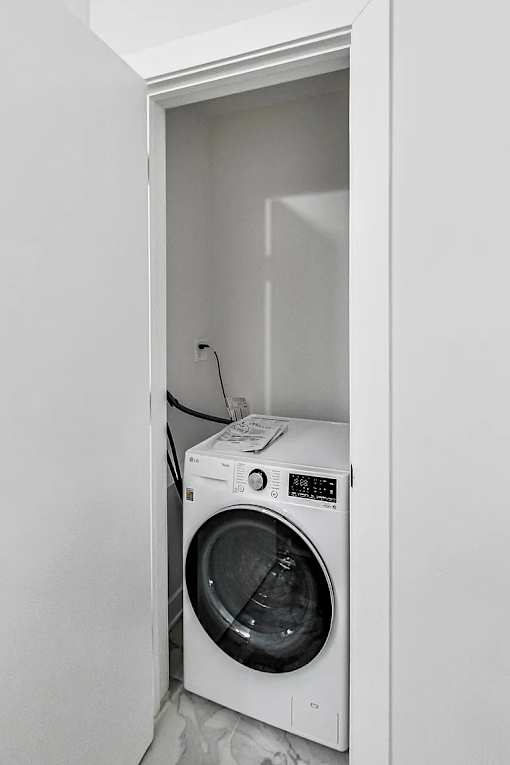A white washing machine is in a white cabinet.