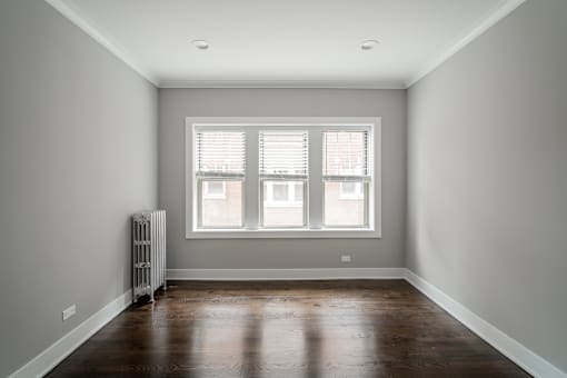 A room with a window and a radiator on the floor.