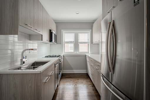 A modern kitchen with a refrigerator on the right and a sink on the left.