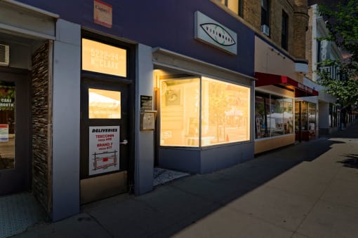 the front of a store at night with the lights on in the window