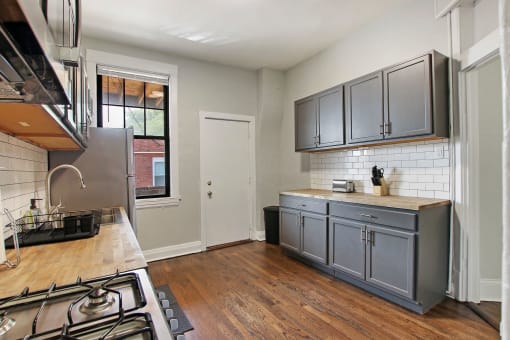 a kitchen with gray cabinets and a stove and a sink