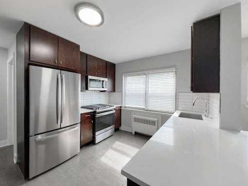 an empty kitchen with stainless steel appliances and white countertops