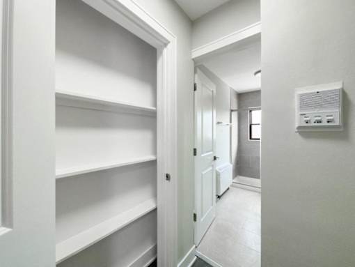 a walk in closet with empty shelves and a door to a bathroom