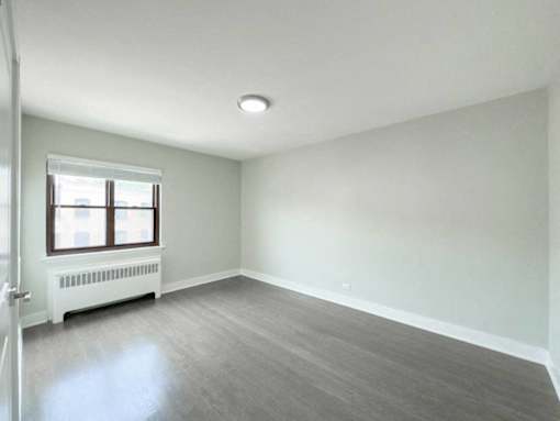 an empty living room with a radiator and a window