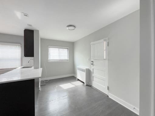 an empty kitchen with white walls and a white door