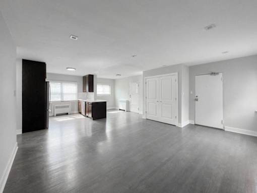 an empty living room and kitchen with white walls and wood floors