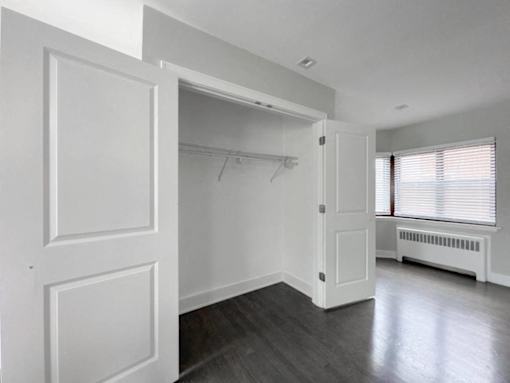an empty room with white walls and a closet and a window