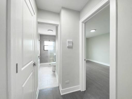 a white hallway with a door open to a bathroom