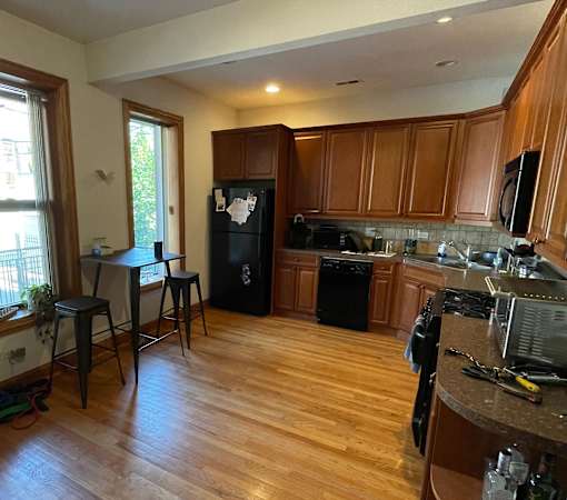 A kitchen with wooden cabinets and a black fridge.