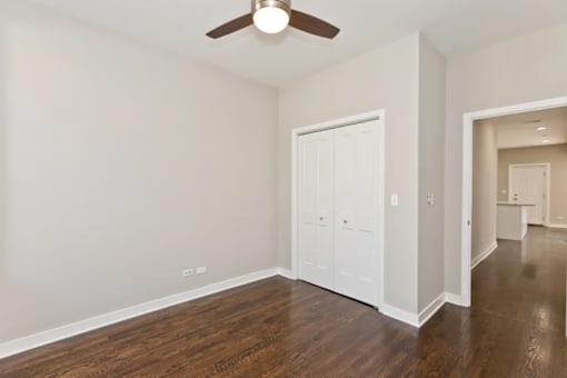 A room with a ceiling fan and wood flooring.