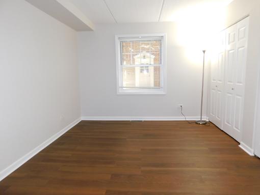 A room with wooden floors and a window with blinds.