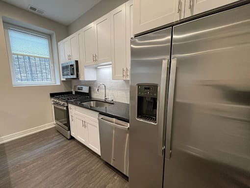 A kitchen with a stainless steel refrigerator and white cabinets.