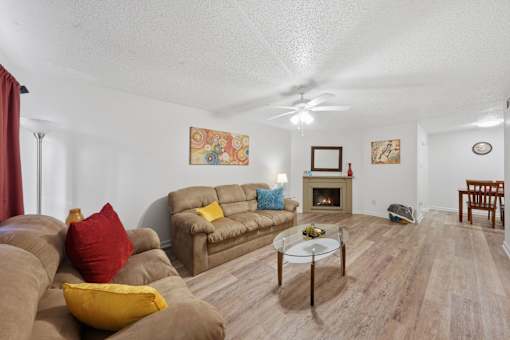 A living room with a brown couch and a glass coffee table.