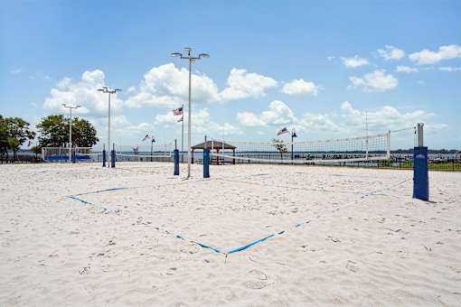 A beach with blue flags and a fence.