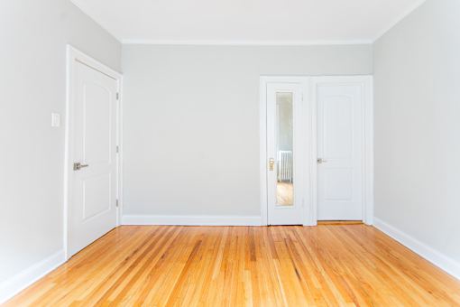 A room with wooden floors and white walls with two doors.