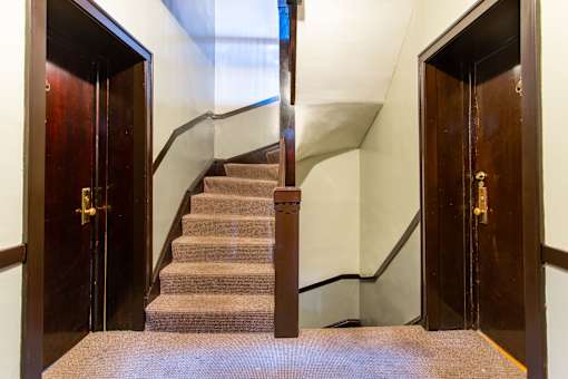 A staircase with a carpeted runner and wooden steps.