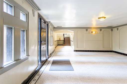 A hallway with a staircase in the background and a light on the ceiling.