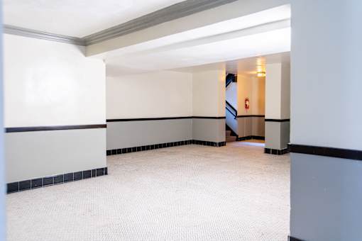 A hallway with a staircase in the background.
