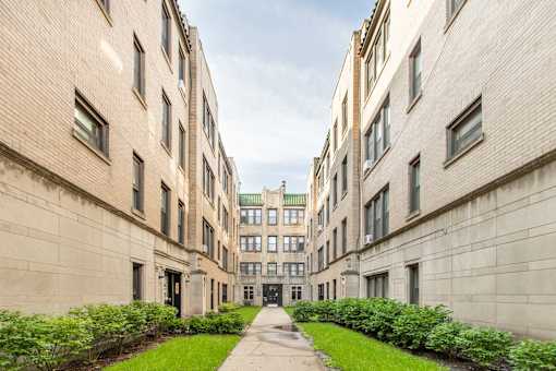 A long, narrow courtyard between two buildings with greenery on the sides.