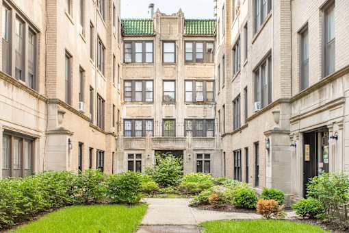 A courtyard surrounded by buildings with a green roof.
