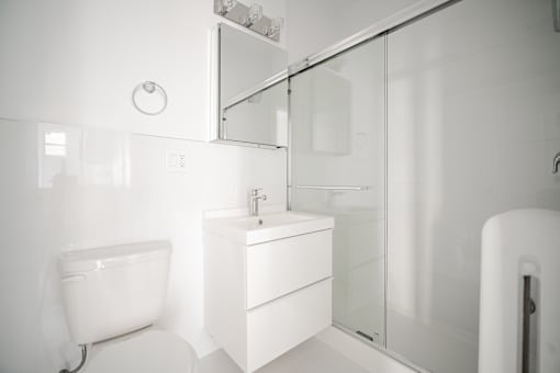 A white bathroom with a sink, toilet, and shower.