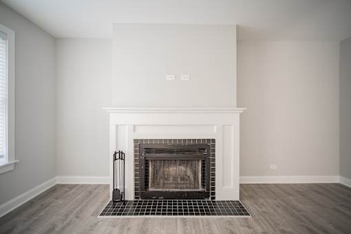 A fireplace with a black grate in a room with white walls.
