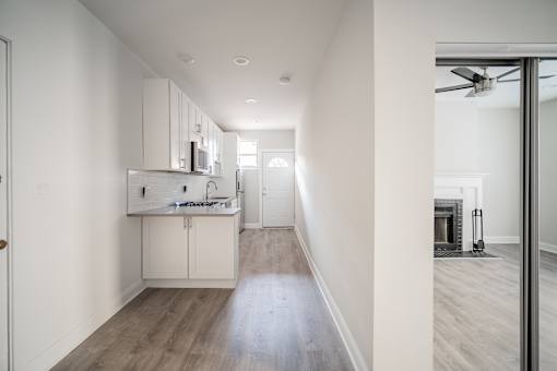 A modern kitchen with white cabinets and a wooden floor.