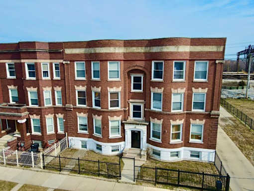 A red brick building with a black fence in front.
