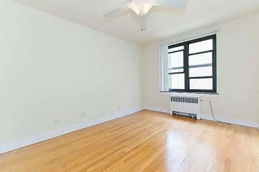 A room with a window and a radiator on the floor.