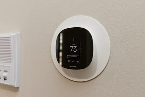 A round thermostat with the number 73 on it is mounted on a wall.