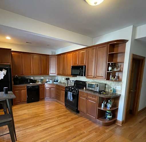 A kitchen with wooden cabinets and black appliances.