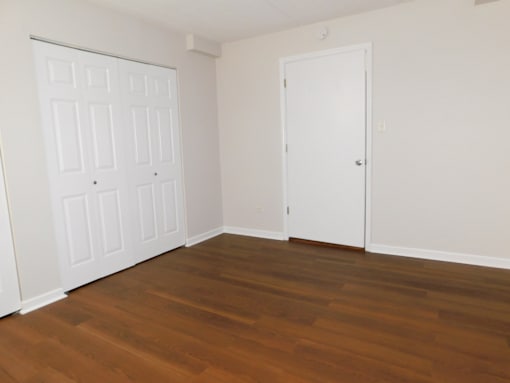A room with a white door and a brown floor.