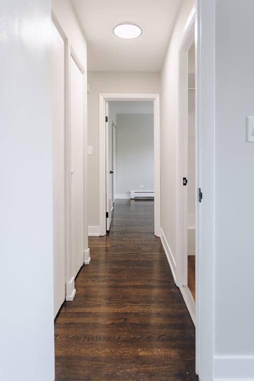 a hallway with wood floors and white walls and a white door