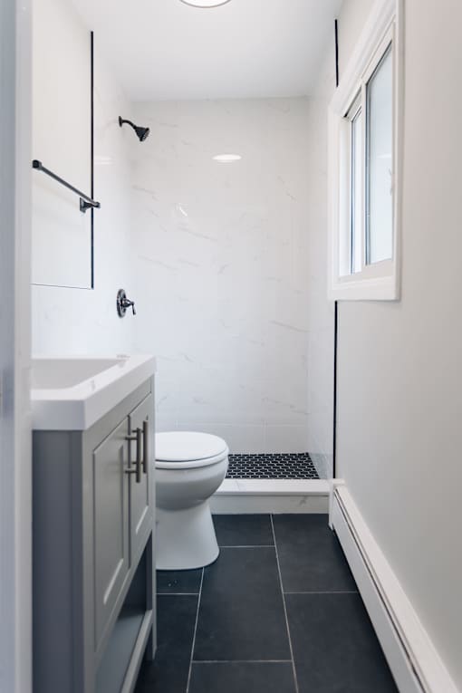 a white bathroom with a toilet and a shower