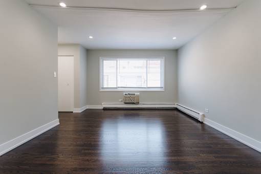 an empty living room with wood floors and a window