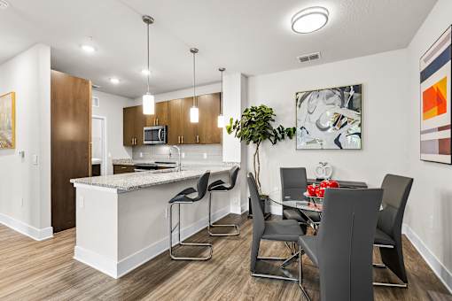 A kitchen with a bar area and a dining table with chairs.
