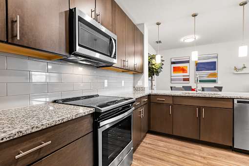 A modern kitchen with a granite countertop and stainless steel appliances.