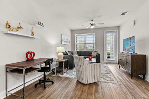 A room with a desk, chairs, and a painting on the wall.