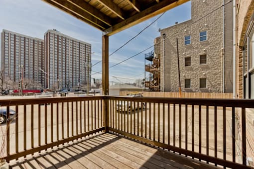 A wooden deck with a railing and a view of a cityscape.