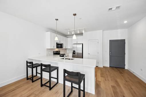 A kitchen with a white counter and black chairs.