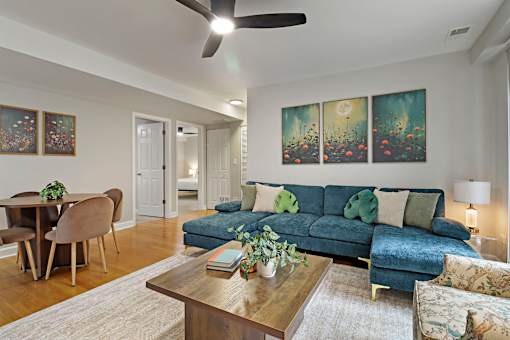 A living room with a blue couch and a ceiling fan.