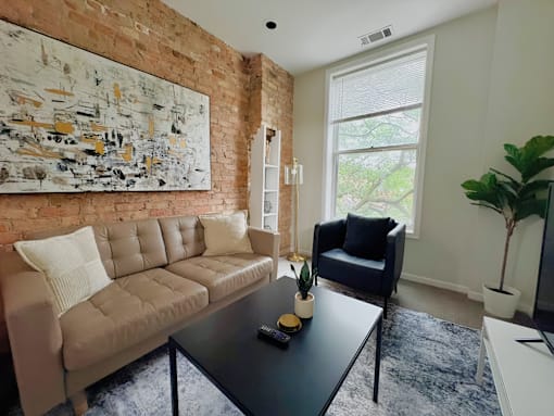 A living room with a couch, chair, and a painting on the wall.