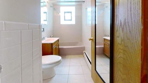 A white tiled bathroom with a toilet, sink, and bathtub.